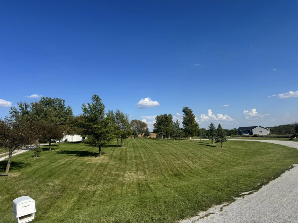 A large property with a beautifully mowed lawn and visible stripes, demonstrating expert lawn care from Bramble Clean Cut Lawn Care LLC in Independence, MO.