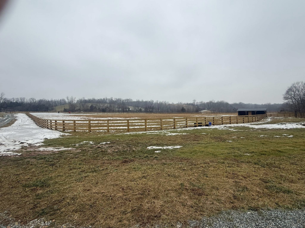 A large property with a newly installed wooden fence enclosure and barn by Richards Fencing in Lynnville, TN
