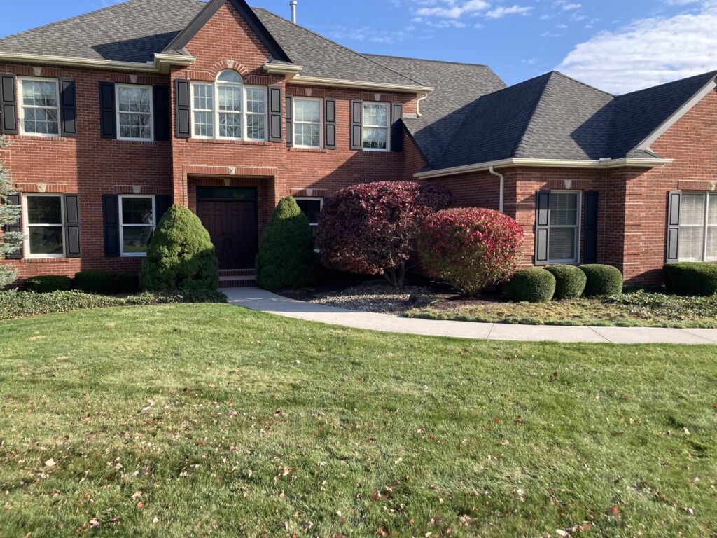 A large residential property with a perfectly manicured lawn and trimmed shrubs by Three Rivers Lawn Care Co. in Fort Wayne, IN.