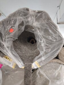 A large roll of gray textured carpet, wrapped in plastic, ready for installation by Truly Carpet in Cleveland, OH.