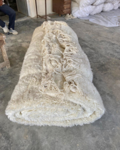 A large, rolled white shaggy carpet ready for installation or delivery by Legacy Looms in Minneapolis, MN.