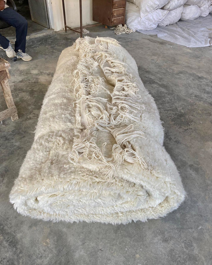A large, rolled white shaggy carpet ready for installation or delivery by Legacy Looms in Minneapolis, MN.