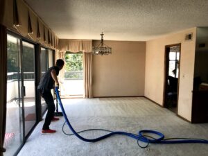 A professional cleaning a large carpeted room with a cleaning wand and hose for Mark it Clean Carpet & Upholstery Cleaning Long Beach, CA.