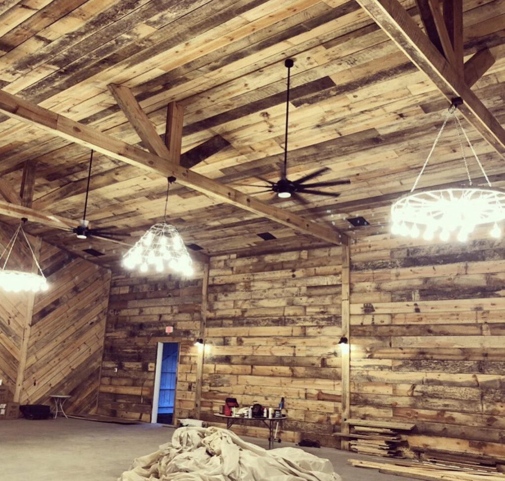 Large room with wooden walls and ceiling, showcasing multiple chandeliers and ceiling fans installed by E-Systems Electrical Inc. in Cumming, GA.