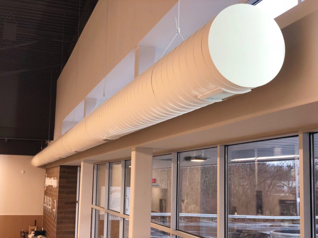 A large, round, exposed HVAC duct installed in a commercial interior by Air-Flow Mechanical Services, Inc. in Cincinnati, OH.