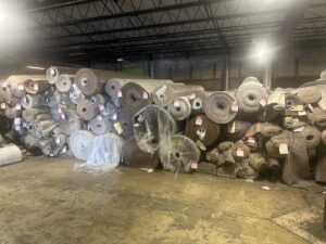 A large selection of carpet rolls stacked in the warehouse at The Carpet Store Tampa, FL