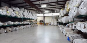 A large warehouse filled with numerous rolls of carpet, showcasing the extensive inventory at Don's Floor Gallery in Edmond, OK.