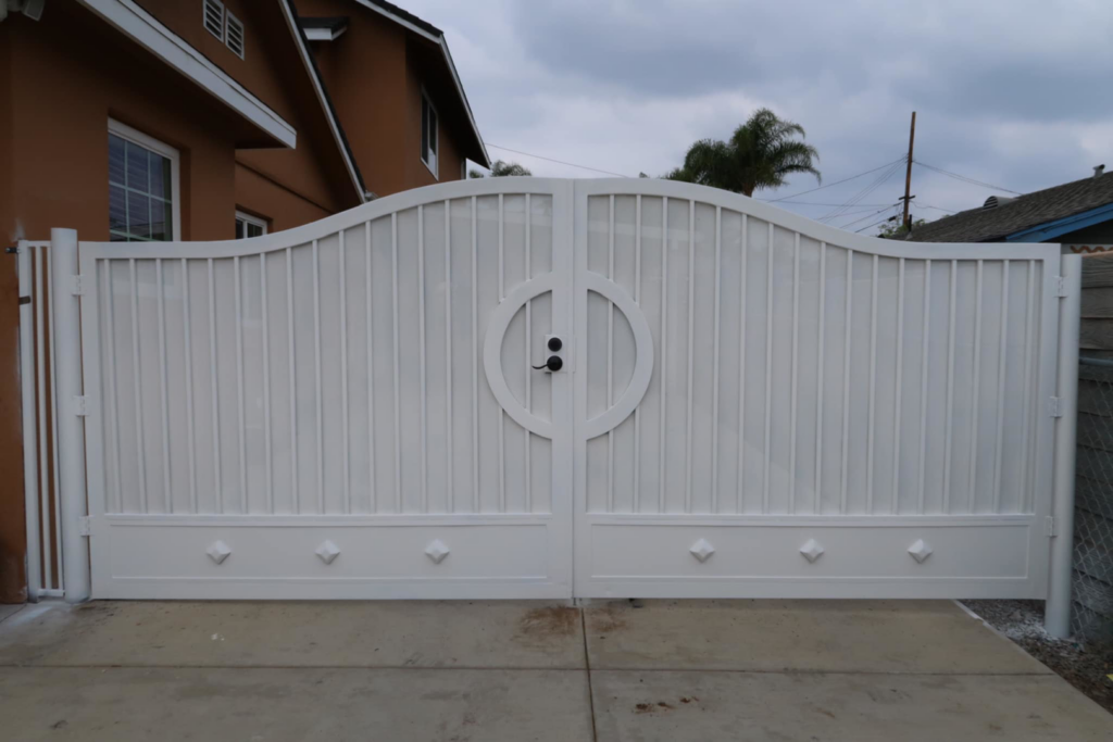 A large white double driveway gate with a curved top, a completed project by Portugal's IronWorks in Los Angeles, CA.