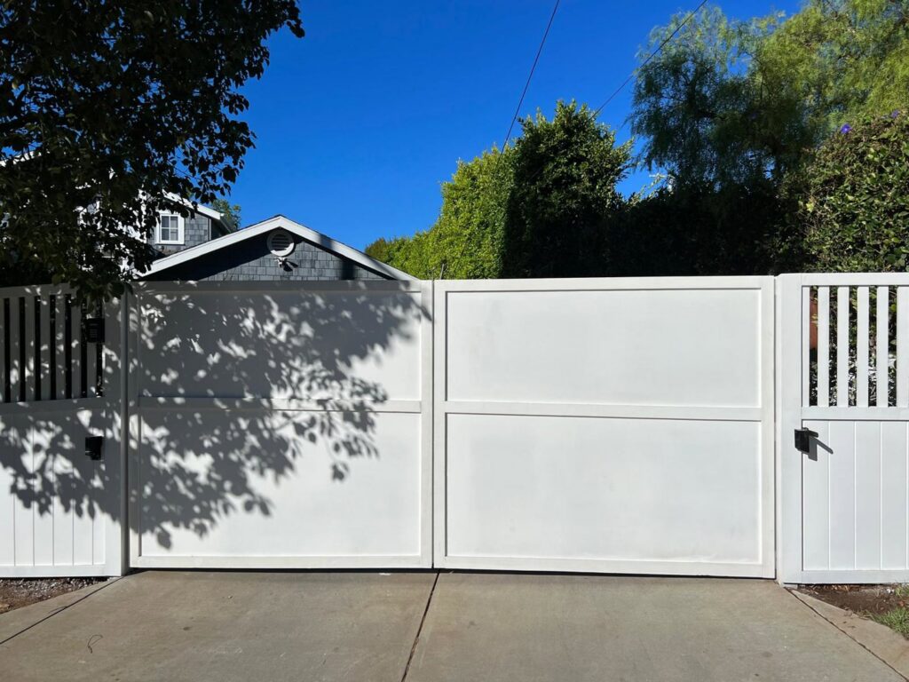 A large white double gate providing secure entry to a property, installed by Harwell Fencing & Gates Inc. in Los Angeles, CA.