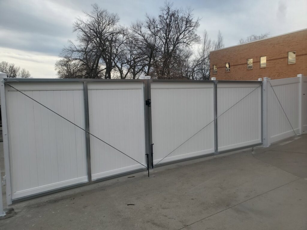 A large white vinyl double gate installed for a commercial property by Pride Fence in Peabody, MA.