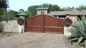 A large wooden double gate with stone pillars, decorated for the holidays, installed by Automated Entry Systems Inc in Escondido, CA.