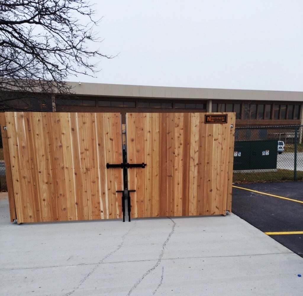 A large wooden double gate with a Northway Fence sign, installed by Northway Fence in Menomonee Falls, WI.