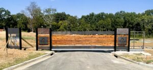 A large, custom wooden and metal entrance gate for a community, built by The Fence Man in Fort Smith, AR.