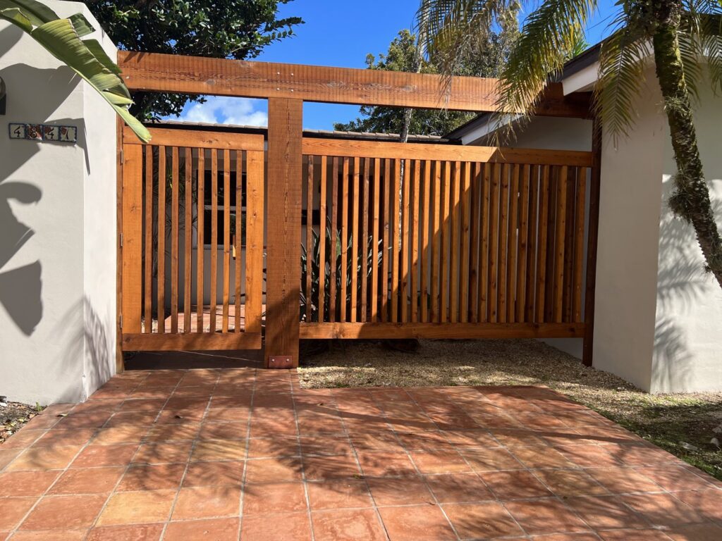A large wooden gate with vertical slats installed as part of a fence system by Miami Fence Installation Contractors in Miami, FL.