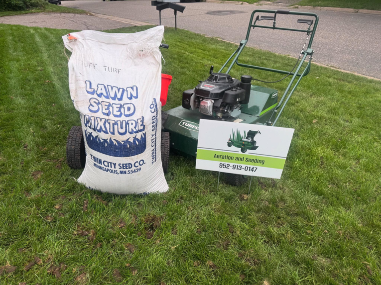 A lawn aerator machine and a bag of lawn seed mixture on a residential lawn, ready for service by Nice Grass Minnesota LLC in Minneapolis, MN.
