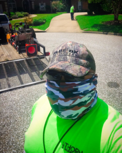 A Thorn Lawn Service crew member with equipment on a trailer, and another worker using a blower in Montgomery, AL.