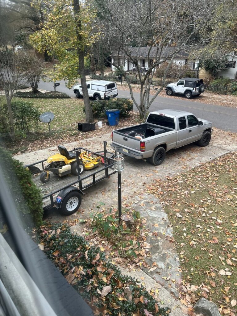 A truck and trailer with a riding lawn mower, ready for a job by Town and Country Grounds Care in Homewood, AL.