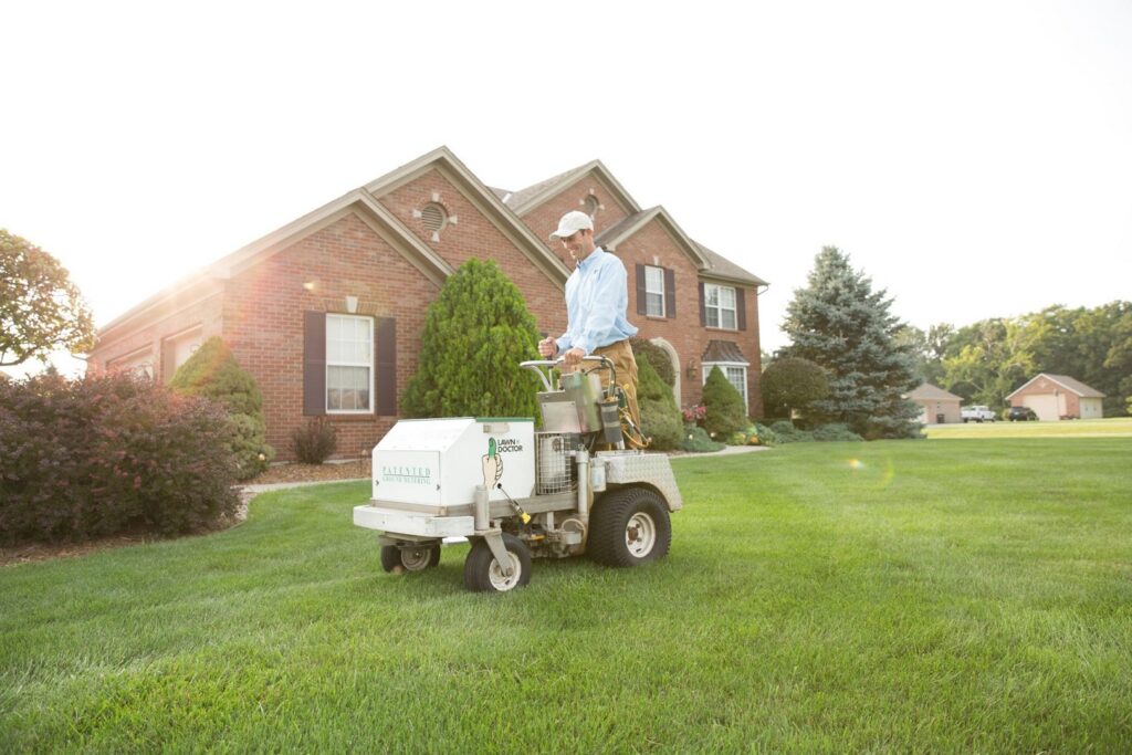 A Lawn Doctor professional operating a lawn aeration machine on a residential lawn in Carmel, IN.