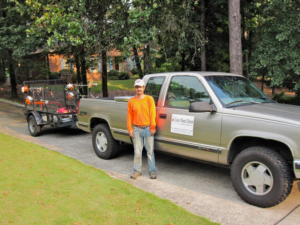 A lawn care professional with a branded truck and equipment trailer from Guy Next Door Lawn Care, LLC in Birmingham, AL.