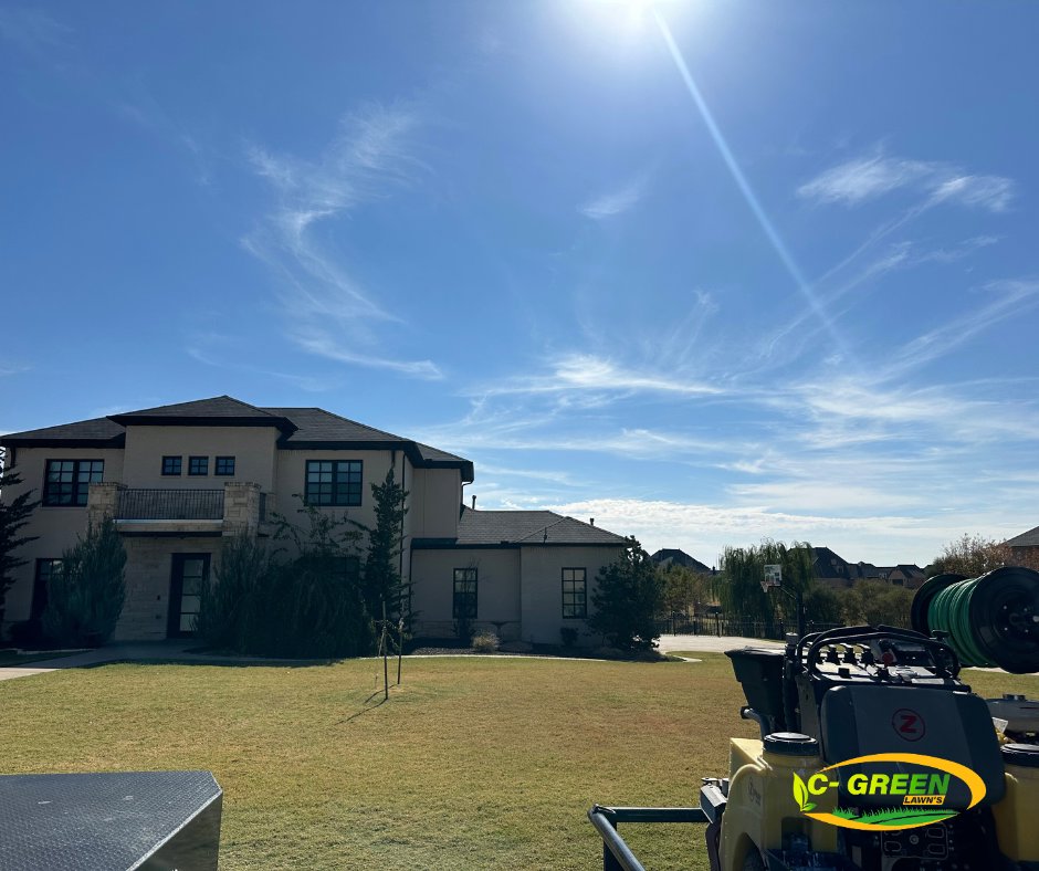 Professional lawn care spreader equipment on a vibrant green lawn under a blue sky by C-Green Lawns in Yukon, OK.