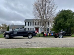 A Roots Lawn Care Solutions truck and trailer with professional equipment parked on a residential street in Granger, IN.