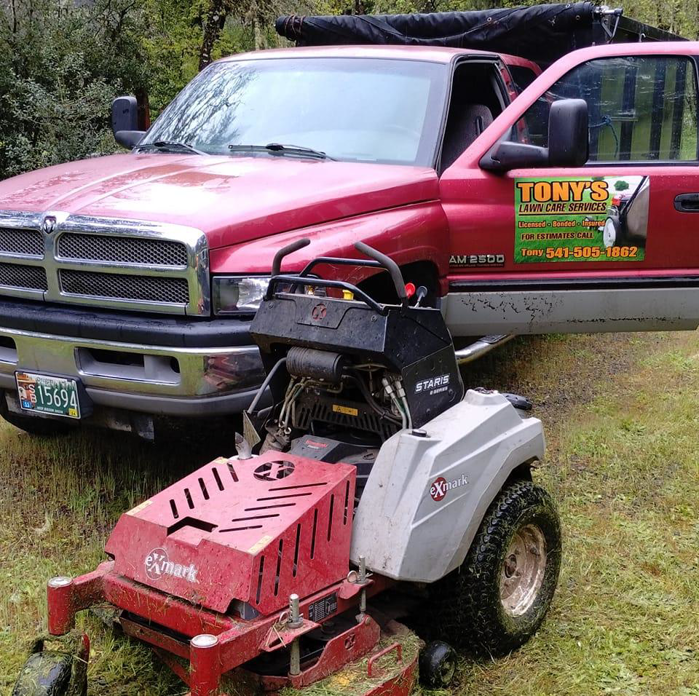 A red pickup truck with Tony's Lawn Care Services decal and a commercial lawnmower, ready for work in Greenville, SC.