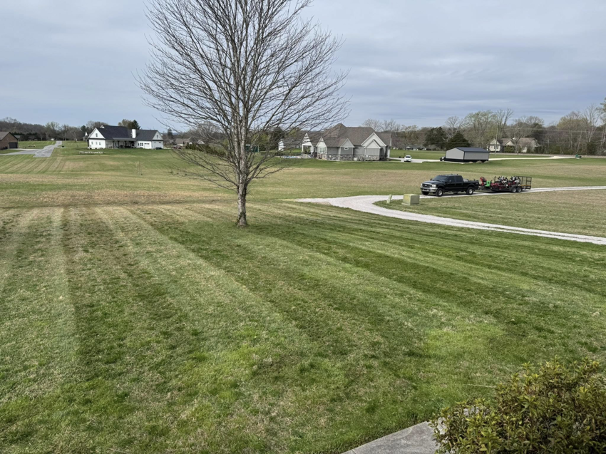 A professional lawn care truck with a trailer full of equipment on a large property, serviced by Hancock Lawn Care in Knoxville, TN.