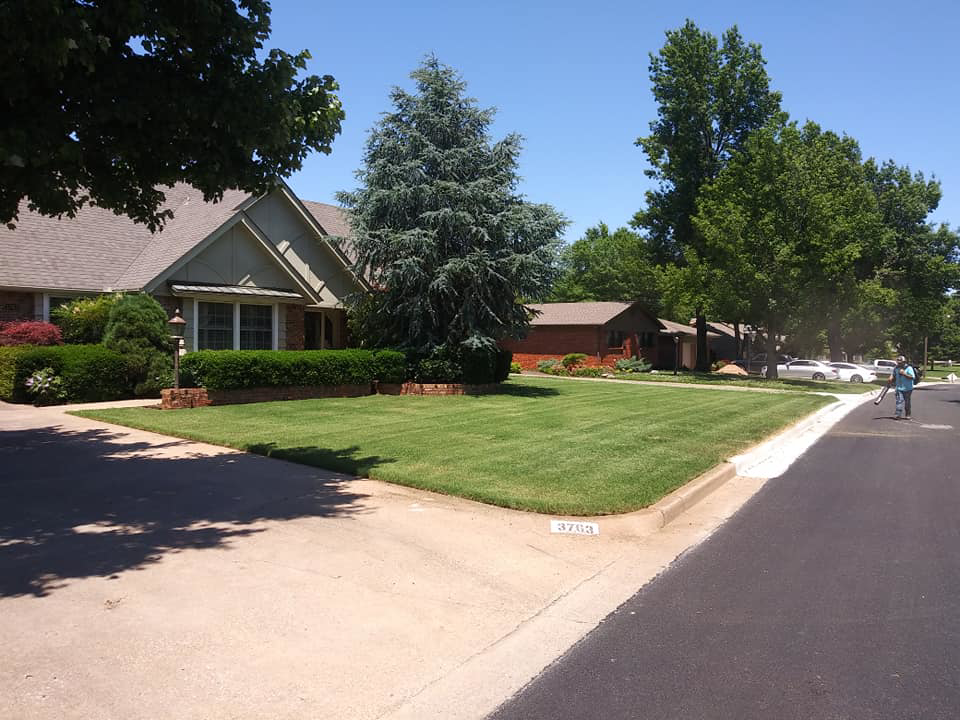 A lawn care worker edging a curb on a neatly mowed lawn, provided by K&R Lawn Care in Pass Christian, MS.