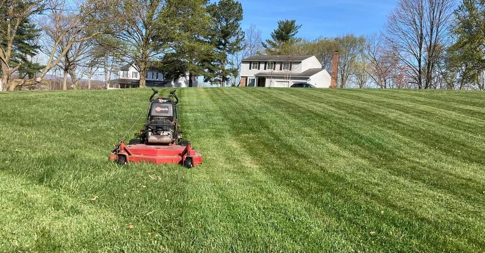 A commercial lawn mower creating perfect stripes on a large lawn by As Green Lawncare and Landscaping LLC in Frederick, MD.