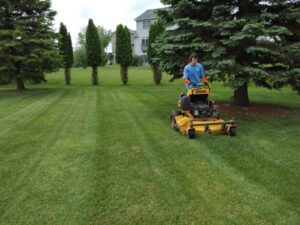 A Three Boys Lawncare professional operating a zero-turn mower, providing expert lawn mowing service in Rochester, MN.