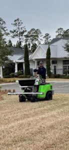 A Pro Care Lawn and Pest technician using a ride-on spreader for lawn pest control in Jacksonville, FL.