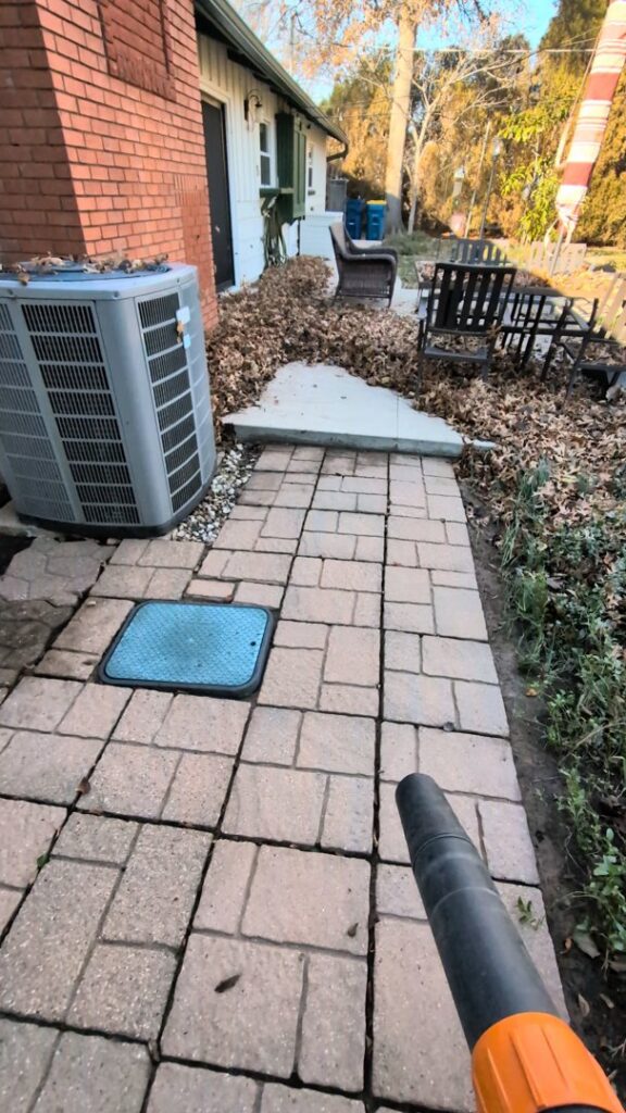 A leaf blower clearing debris from a paved patio during a property cleanup by Redline Mowing & Trimming in Stillwater, OK.