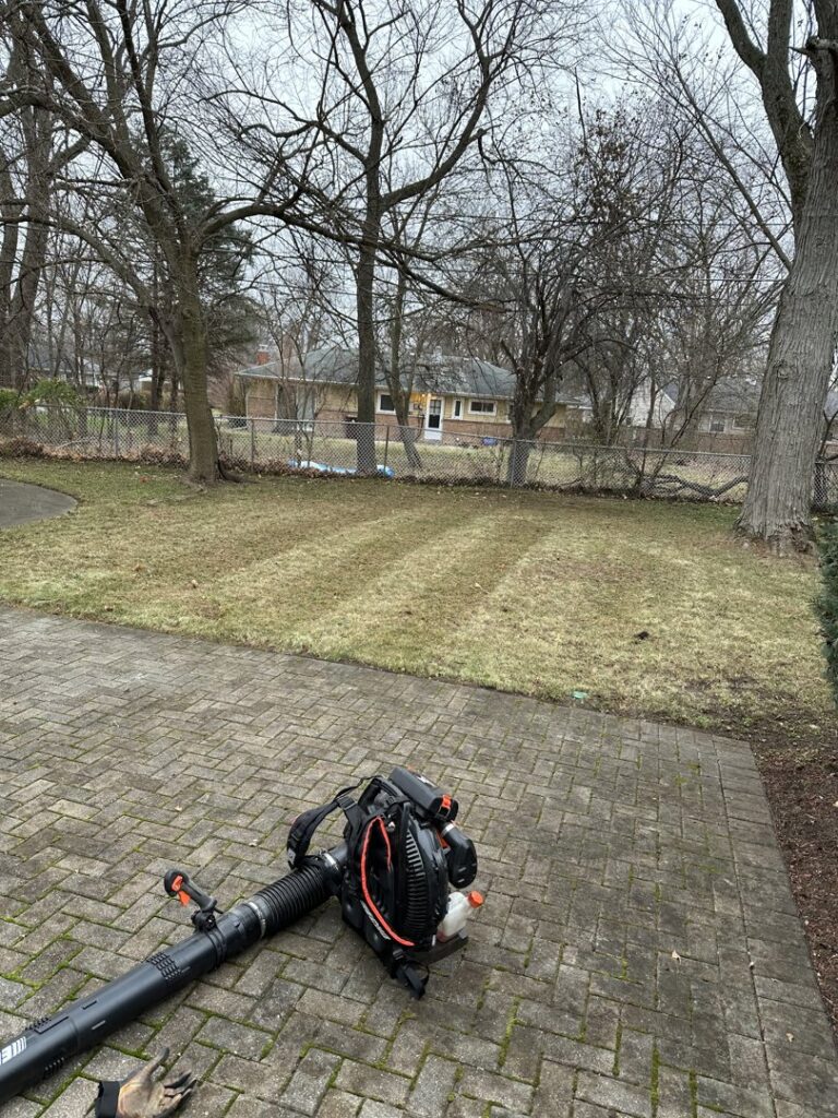 A leaf blower on a brick patio next to a lawn, indicating cleanup services by Geno's Father & Son Lawn Services Llc in Hammond, IN