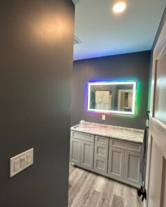 Modern LED-lit mirror and light switches installed in a bathroom by Breakers Electric LLC in Dover, NH.