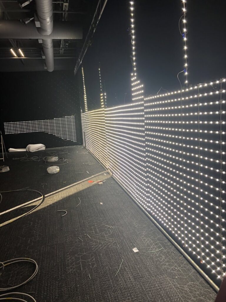 Custom LED strip lighting installed on walls in a dark room, highlighting specialized lighting services by Veritas Electric in Yalaha, FL.