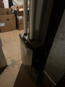 A Lennox furnace unit with PVC venting pipes, indicating a professional HVAC installation by Crain Heating and Cooling in Jeffersonville, IN.