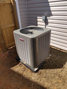 A Lennox outdoor HVAC unit professionally installed next to a residential house and wooden fence by NAS Heating & Air in Fayetteville, NC.