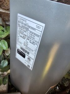 A close-up of a Lennox outdoor HVAC unit's specification label, showing model and electrical data, serviced by MasterCraft Mechanical, LLC. in Haslet, TX.