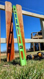 A level leaning against a wood fence during installation, ensuring precision by Hotshot Fencing and Gates in Kansas City, MO.