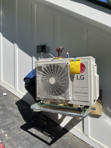 An LG Smart Inverter outdoor HVAC unit being installed on a wall bracket by West Mechanical in Summerville, SC.