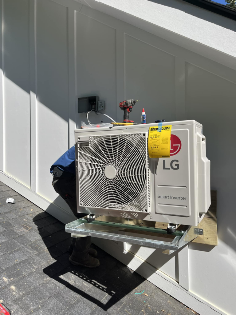 An LG Smart Inverter outdoor HVAC unit being installed on a wall bracket by West Mechanical in Summerville, SC.