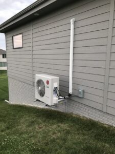 An LG mini-split outdoor unit professionally installed on the side of a home by Comfort Solutions Heating and Air Conditioning in Omaha, NE.