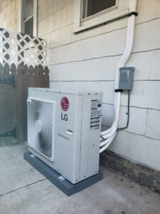 An LG Smart Inverter outdoor HVAC unit newly installed next to a residential building by Tack Mechanical LLC in Baltimore, MD.