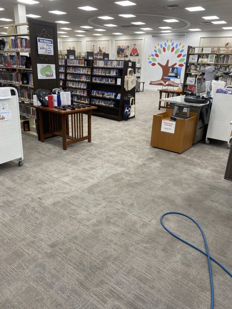 A commercial carpet in a library setting being cleaned, with a blue hose visible, by B of C Carpet Cleaning LLC in Idaho Falls, ID.