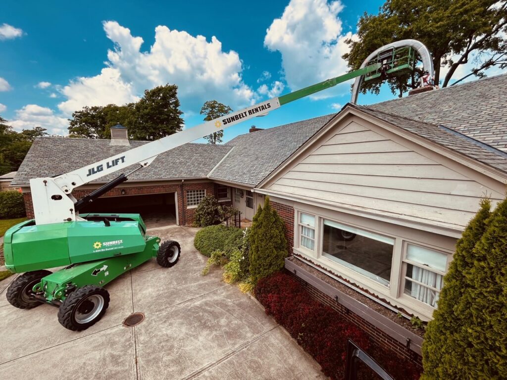A lift bucket extended over a residential house, positioned for chimney service or repair by Century Chimney Sweep and Repair in Cleveland, OH
