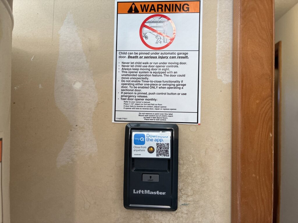 A LiftMaster garage door opener control panel with a warning label, installed by Coast To Coast Garage Door LLC in Vancouver, WA.