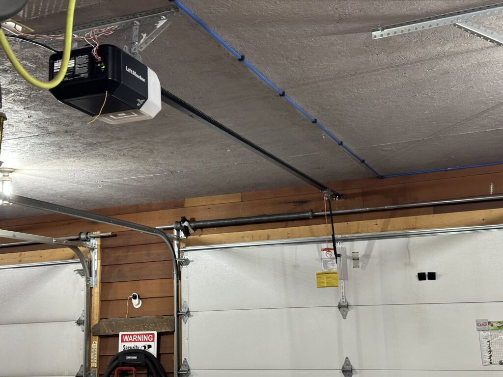 A LiftMaster garage door opener and tracks installed in a garage by AJK Door Services in Duluth, MN.