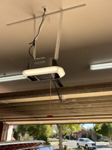 A LiftMaster garage door opener installed on the ceiling above an open garage door by Stapley Action Garage Door in Mesa, AZ.