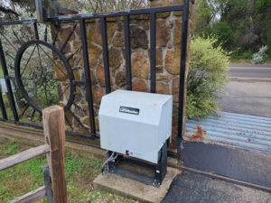 A LiftMaster gate opener installed next to a decorative metal gate and stone pillar by S.A. SAF-T Systems, LLC in San Antonio, TX.