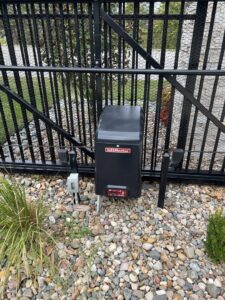 A LiftMaster gate operator installed on a black metal fence by Brothers Gate Operators and Services LLC in Olathe, KS.